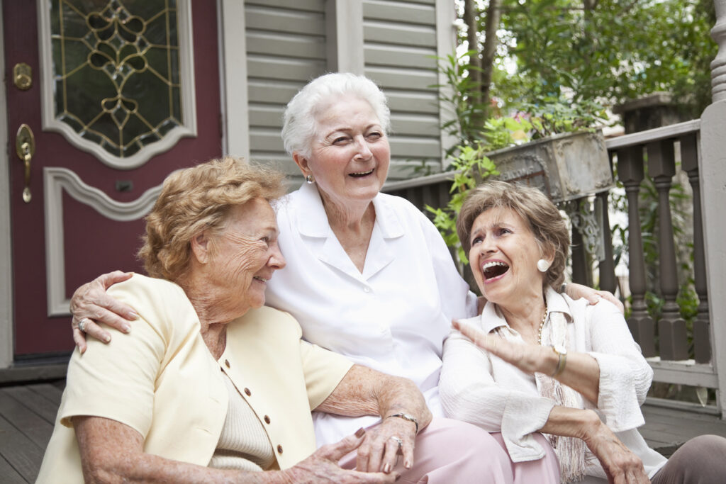 Three elderly women sitting in front of home