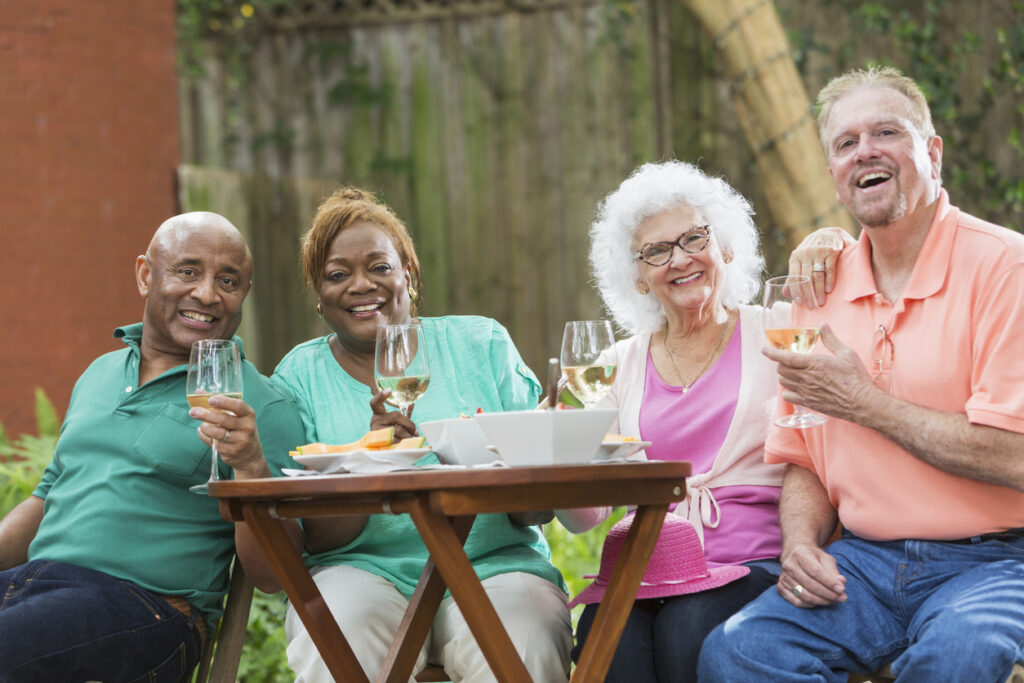 Group of seniors enjoying wine and food in back yard